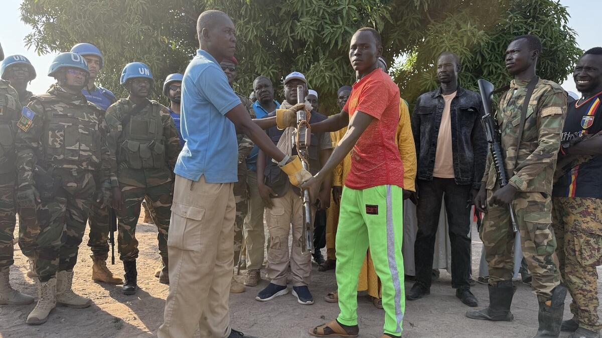 Deux hommes se serrent la main devant un groupe de soldats de la paix en uniforme militaire.