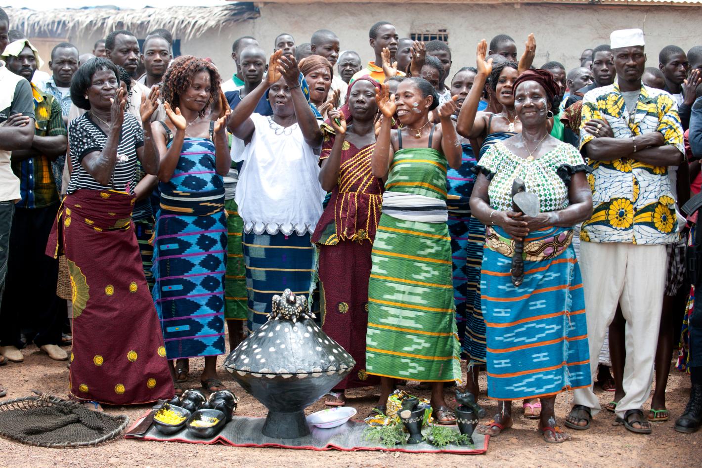 A group of people standing in front of some traditional items wearing traditional clothing