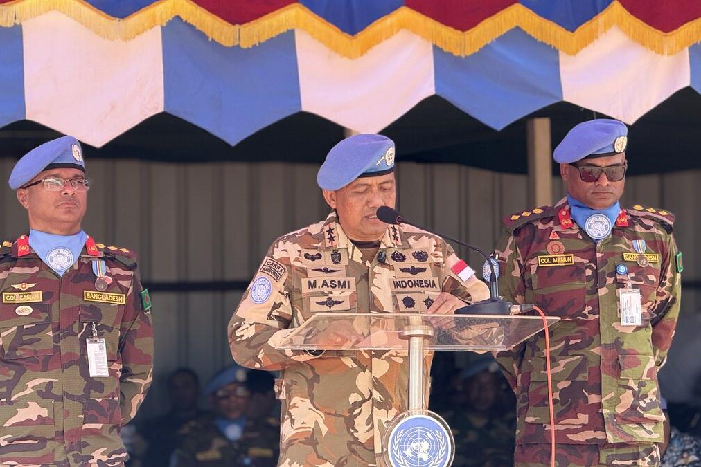 Un casque bleu parle à un public depuis un podium. 