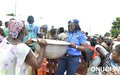 Distribution d’eau potable en marge des Journées des Nations Unies à Vavoua : une Policière de l’ONUCI aide une femme à mettre sa bassine remplie d’eau sur la tête (Vavoua, mai 2016)