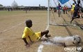 A footballer scores with determination during the 