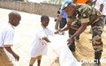 Opération de salubrité organisée en marge de la 42e édition des Journées des Nations Unies : un officier de la Force onusienne aide des enfants au ramassage de feuilles mortes (Dimbokro, février 2016)