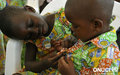 Village SOS d’Abobo en décembre 2011 : une fillette aide son jeune ami à bien fermer les boutons de sa chemise