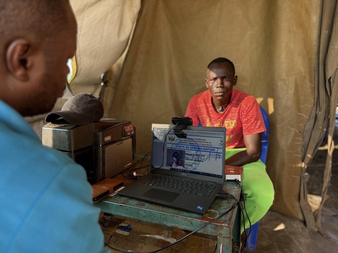 Un homme est assis devant un ordinateur, avec une caméra vidéo dessus.
